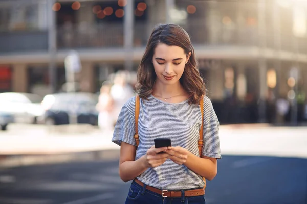 stock image Connected to her friends in all parts of the city. an attractive young woman sending text messages while spending her day out in the city