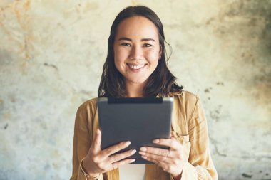 Bağlı olduğum sürece mutlu olurum. Duvarın önünde dikilirken dijital tablet kullanan genç bir kadının portresi