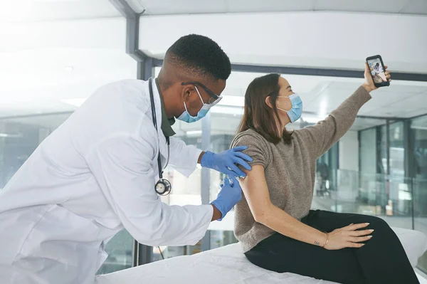 stock image I need to get this on camera. a young doctor giving a patient an injection while she takes a selfie in an office