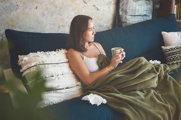 感情をつかまえろインフルエンザじゃない 自宅のソファで病気から回復しながら温かい飲み物を飲んでいる若い女性が — ストック写真