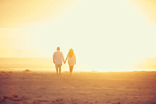 太陽が彼らの愛に輝きましょう ビーチで手をつないで歩く愛情のある成熟したカップルのレビューショット — ストック写真