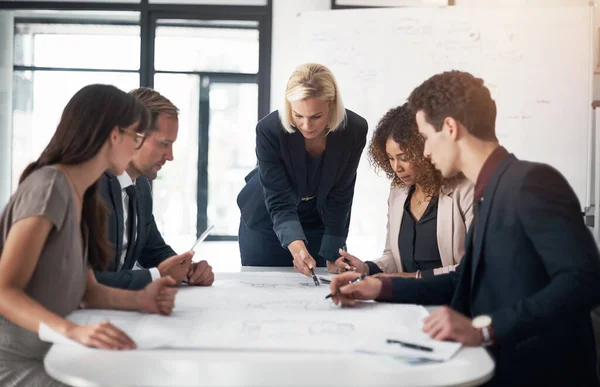 stock image These plans need more precision. a team of professionals working on blueprints in an office