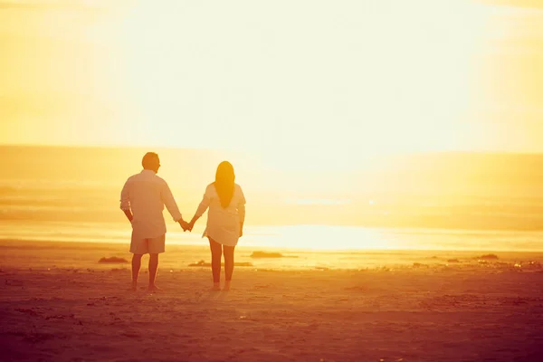 一起在天堂里一对深情的成熟夫妇手牵着手在海滩上散步的背景图片 — 图库照片