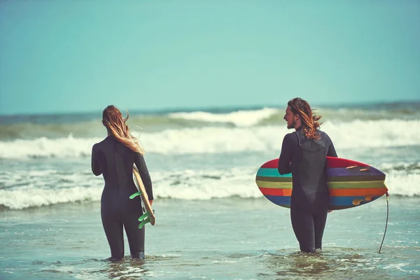 ベイで休暇をサーフィン ビーチでサーフィンをしている若いカップルが — ストック写真