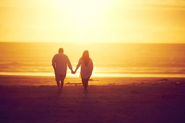 夕日と日の出を通して一緒に ビーチで手をつないで歩く愛情のある成熟したカップルのレビューショット — ストック写真