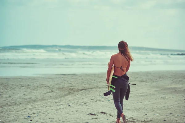 波があなたを取るところへ行きます ビーチでサーフボードを担いでいる若いサーファーが — ストック写真