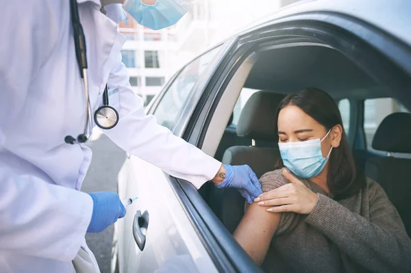 Play your part, get your shot. a masked young woman receiving an injection at a Covid-19 drive through testing centre