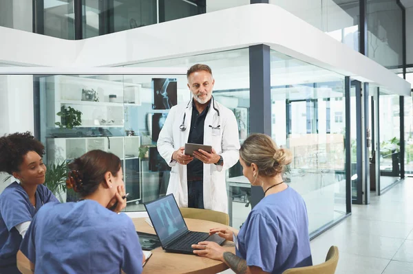 stock image Providing support and supervision to his team. a mature doctor leading a discussion with his colleagues in a hospital