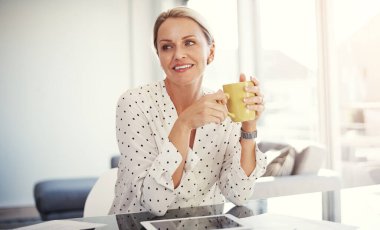 Güne başlamak için bir fincan taze kahve gibisi yoktur. Olgun bir iş kadını ev ofisinde çalışıyor.