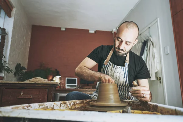 Let your art lead the way. a young man working with clay in a pottery studio
