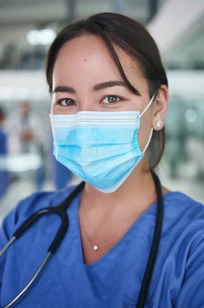 細菌ではなく 思いやりを広める 顔のマスクをした魅力的な若い看護師のトリミングされた肖像画と診療所で一人立ち — ストック写真