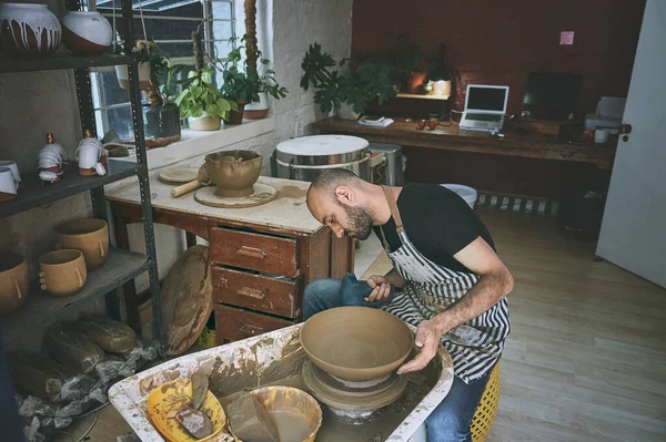 Modern tools for an ancient craft. a young man working with clay in a pottery studio