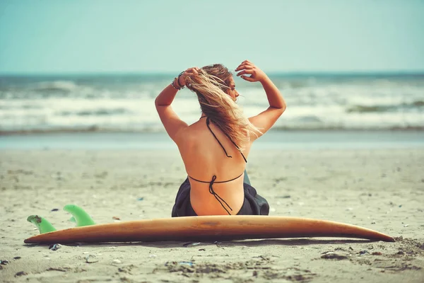 波がどこにいようとも ビーチでサーフィンをしている美しい若い女性が — ストック写真