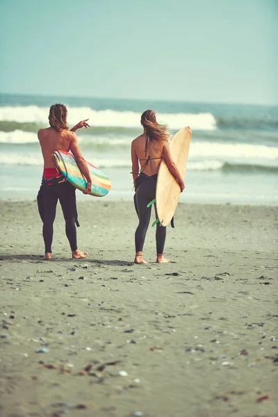 完璧な波がやって来るのが見える 若いカップルがサーフボードを持ってビーチを歩いていて — ストック写真