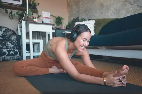 Stock image Feeling the stretch. a young woman stretching her legs while exercising at home