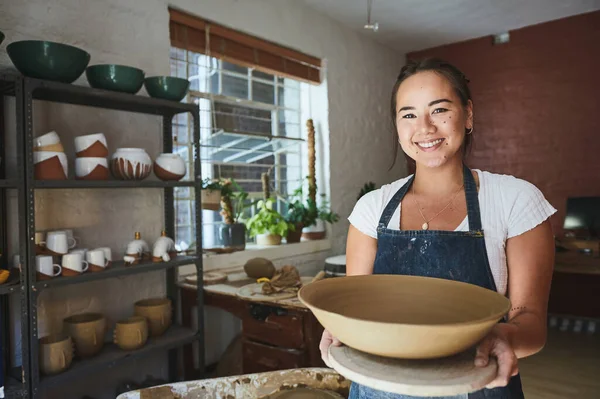 Doesnt it feel good to make it yourself. a young woman making a bowl in a pottery studio