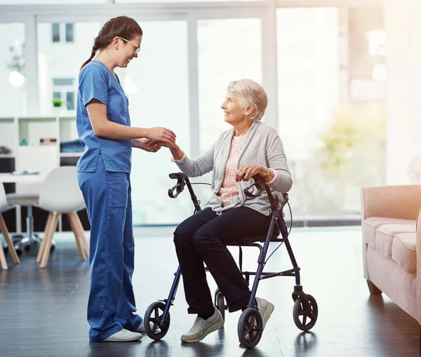 stock image Shes dedicated to her patients. Full length shot of a young female nurse talking to her senior patient in the old age home