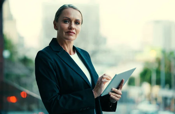 ビジネスの未来に触れる 彼女のオフィスのバルコニーに立っている間 彼女のタブレットを使用して魅力的な成熟した実業家の作物の肖像画 — ストック写真