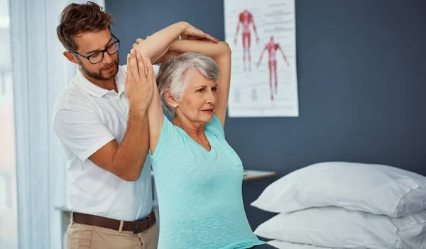 stock image Youve got a good range of movement. a senior woman working through her recovery with a male physiotherapist