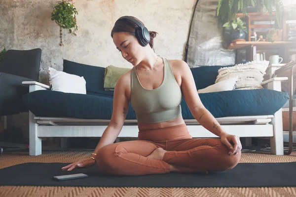 跟随一个有指导的瑜伽应用 在家里锻炼时使用手机的年轻妇女 — 图库照片