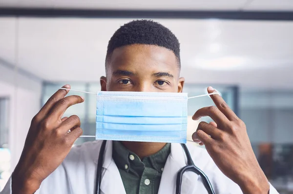 安全を練習しないと 病院に立っている間にマスクをつけたハンサムな若い男性医師のトリミングされた肖像画 — ストック写真