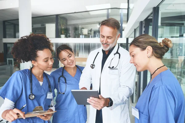 새로운 모든걸바꾸고 잘생긴 의사가 간호사들 토론하는 디지털 태블릿을 사용하고 있습니다 — 스톡 사진