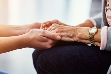 Hastalarını şefkatle tedavi ediyor. Tanınmayan bir kadın hemşire, yaşlı hastalarını rahat ettirmek için elini tutuyor.