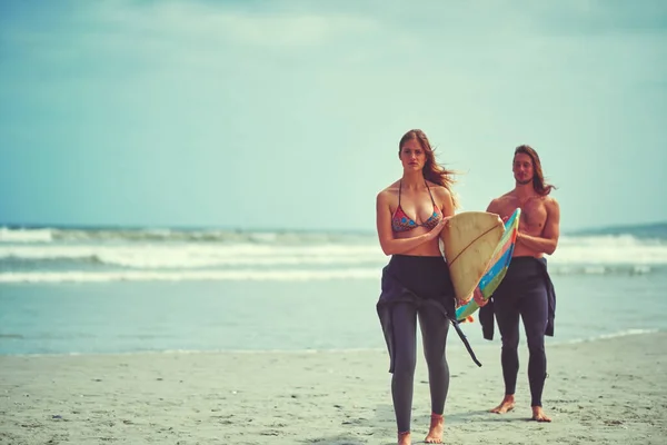 敞开心扉去冲浪 一对带着冲浪板在海滩上散步的年轻夫妇 — 图库照片