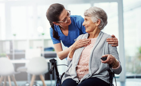 I want your stay here to be as enjoyable as possible. a young female nurse talking to her senior patient in the old age home