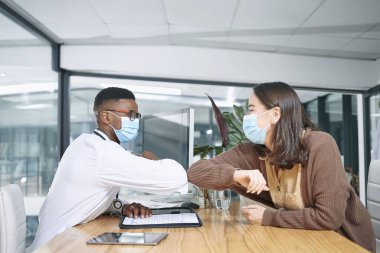 Seni görmek her zaman güzel, Covid zamanlarında bile. Genç bir doktor hastasıyla oturuyor ve klinikte onu dirsek darbesiyle selamlıyor.