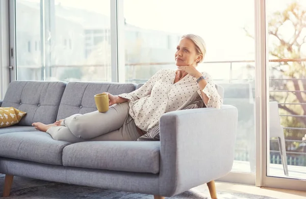 stock image Coffee always help me to plan my day. a happy mature woman relaxing on the sofa at home