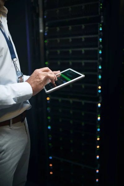 Keeping all data safe and secure. Closeup shot of an unrecognisable man using a digital tablet while working in a server room