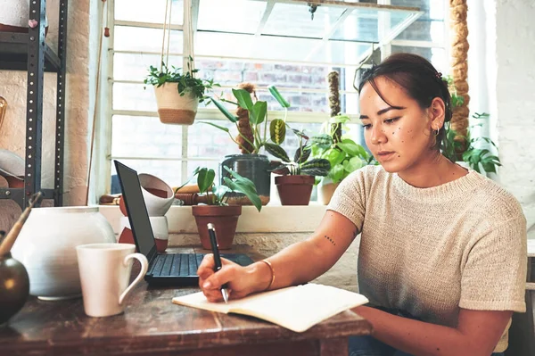 stock image Drawing up a new marketing plan. an attractive young business owner sitting alone in her pottery studio and making notes