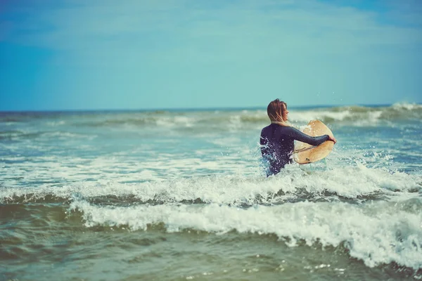 水と一緒に ビーチでサーフィンをしている美しい若い女性が — ストック写真