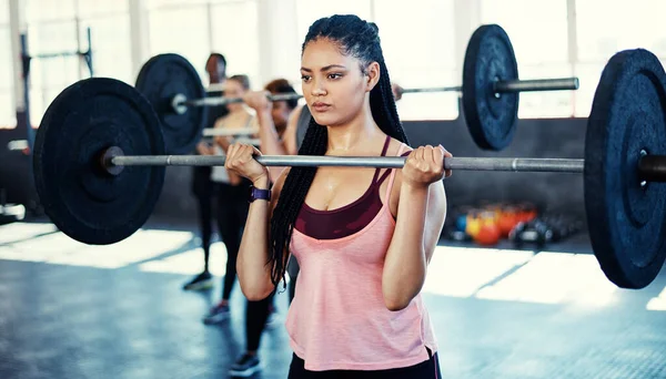 努力增强你的力量 在健身房的时候 一个女人带着一个杠铃在锻炼 — 图库照片