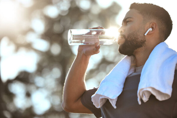 Man, fitness and drinking water in nature for sustainability, hydration or break after running workout or exercise. Male person or runner with natural drink for healthy wellness or rest from run.