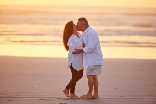 度假对心脏有益 在海滩上亲吻的一对成熟的夫妇 — 图库照片