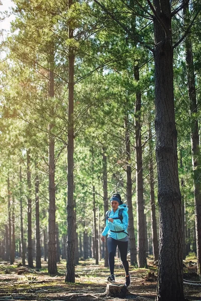 stock image Working on a new me. Full length shot of an athletic young woman out for a jog in the woods