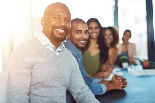 stock image Behind me sits a great team. Portrait of a businessman sitting in a boardroom with his colleagues blurred out in the background