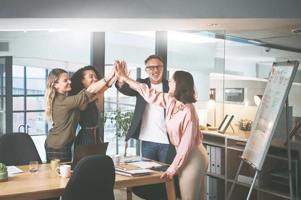 Teamwork gets the work done faster. a diverse group of businesspeople giving each other a high five during a meeting in the office