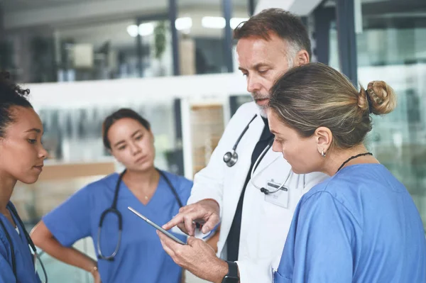 포도당 수치를 잘생긴 의사가 간호사들 토론하는 디지털 태블릿을 사용하고 있습니다 — 스톡 사진