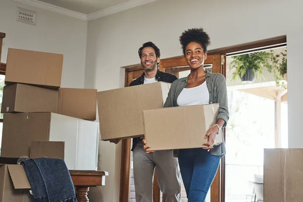 Happy couple, real estate and moving in property with boxes for renovation, investment or relocation. Excited interracial man or woman owner carrying box in move together or mortgage loan in new home.