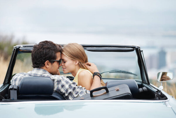 Getting close and sharing a moment. An attractive young couple in their convertible while on a roadtrip