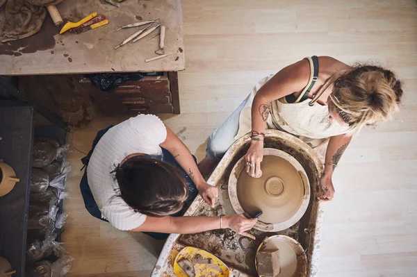 Who cares about the mess when youre making something beautiful. two young women working with clay in a pottery studio