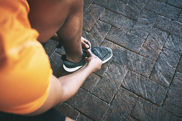 Lace up, lets move. a man tying his shoelaces during a workout against an urban background
