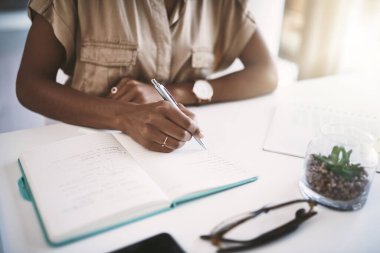 Organizasyon başarının bir göstergesidir. Genç bir iş kadını, modern bir ofiste masasına notlar yazıyor.