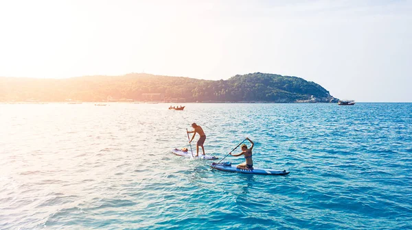 パラダイスを通って最もよい方法はパドルボードにある 海を渡る男と女のパドルボード — ストック写真