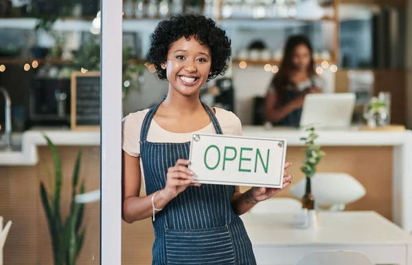Happy woman, open sign and portrait at cafe of waitress or small business owner for morning or ready to serve. African female person at restaurant holding board for coffee shop or cafeteria opening.