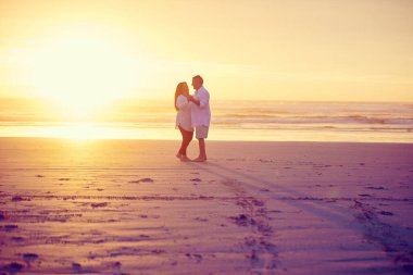 Güneşte aşıklar. Gün batımında kumsalda dans eden sevecen ve olgun bir çiftin tam boy görüntüsü.