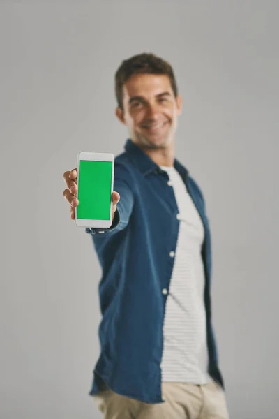 賢い生活をしてる 灰色の背景に緑の画面を持つ携帯電話を保持している若い男のスタジオの肖像画 — ストック写真